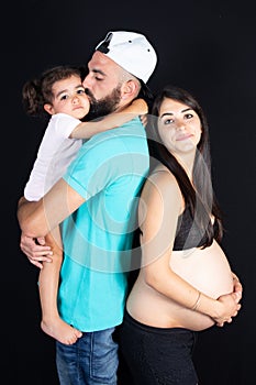 Happy family father and child girl daughter embracing belly of mother pregnant