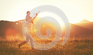 happy family father and child run on meadow with a kite in summer