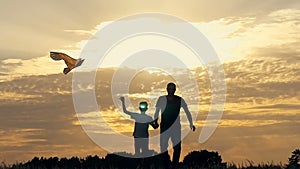 Happy family father and children running in the meadow with a kite in summer at sunset