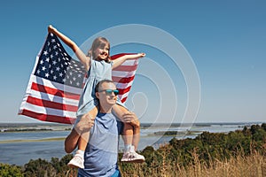 Happy family father and daughter having fun with America flag at sunset outdoors