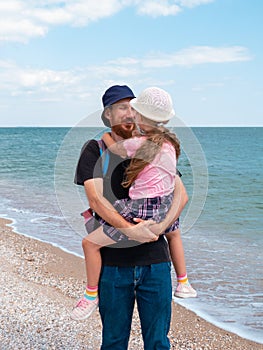 Happy family father daughter hugging on marine landscape. Bearded dad with child in hands having fun together