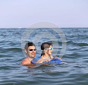 Happy family with father and daughter playing in the sea in summ