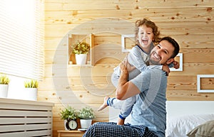 Happy family father and daughter reading book in bed