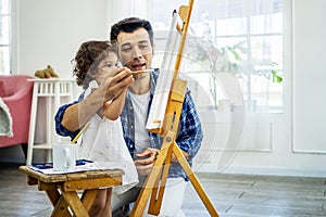 Happy family of father and kid drawing picture, using different paints and brushes.