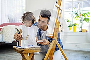 Happy family of father and kid drawing picture, using different paints and brushes.