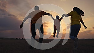 happy family. father mother and baby run play at sunset silhouette holding hands and throw up. happy family in kid dream