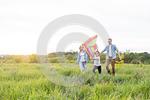 Happy family father, mother and child daughter launch a kite on nature at sunset