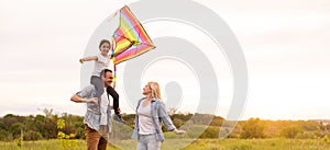 Happy family father, mother and child daughter launch a kite on nature at sunset