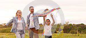 Happy family father, mother and child daughter launch a kite on nature at sunset