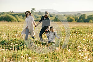 Happy family father, mother and child daughter on nature at sunset