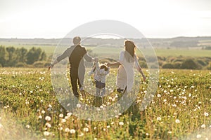 Happy family father, mother and child daughter on nature at sunset