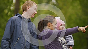 Happy family: Father, Mother and child - little girl in autumn park: mammy shows to baby something