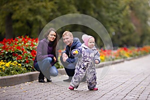 Happy family: Father, Mother and child - little girl in autumn park: playing in the alley with flowers