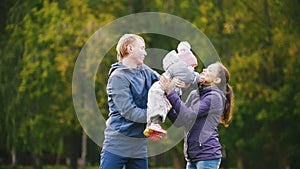 Happy family: Father, Mother and child - little girl walking in autumn park: playing at the grass, slow motion