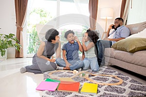 Happy family father and mother and children doing activity playing toy railway with fun in the living room.