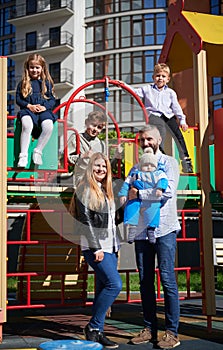 Happy family - father, mother and children having fun together on playground.