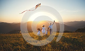 Happy family father, mother and children launch kite on nature