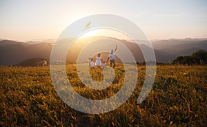 Happy family father,  mother and children launch  kite on nature at sunset