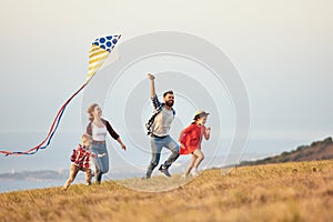 Happy family father,  mother and children launch  kite on nature at sunset