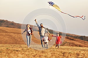 Happy family father,  mother and children launch  kite on nature at sunset