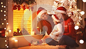 Happy family sitting by fireplace on Christmas Eve