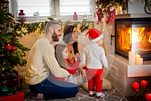 happy family father mother and children sitting by fireplace on Christmas Eve