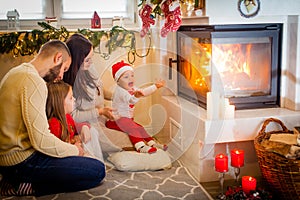 happy family father mother and children sitting by fireplace on Christmas Eve