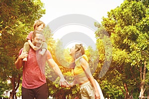 Happy Family. father, mother with little child in the park on a sunny summer day together. Son sitting on his father shoulders