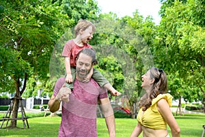 Happy Family. father, mother with little child in the park on a sunny summer day together. Son sitting on his father shoulders
