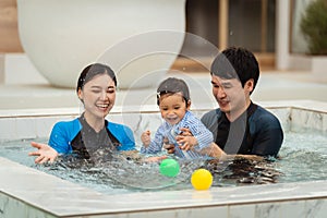 happy family. father and mother with small daughter in swimming pool