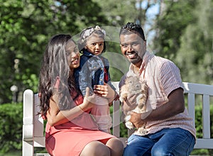 happy family father, mother and small girl with a rabbit in a city park