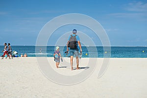 Happy family of father, mother and son goes vacation on a tropical sand beach in summer. Dubai beach