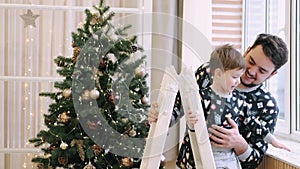 Happy family of father and son near Christmas tree at home