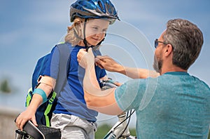 Happy family. Father and son riding bike in park. Child in safety helmet with father riding bike in summer day. Father