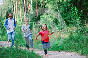 Happy family - father with two kids - run play in nature