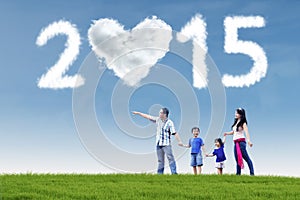 Happy family in field under cloud of 2015
