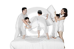 Happy family fighting with pillows on studio