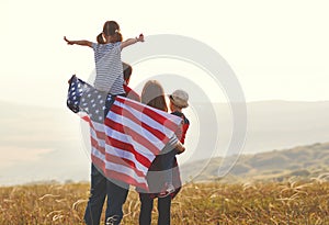 Happy family with flag of america USA at sunset outdoors