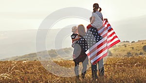 Happy family with flag of america USA at sunset outdoors