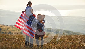 Happy family with flag of america USA at sunset outdoors