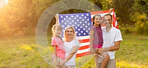 happy family with the flag of america USA at sunset outdoors