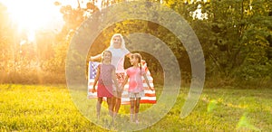 happy family with the flag of america USA at sunset outdoors