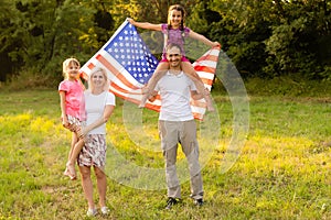 happy family with the flag of america USA at sunset outdoors