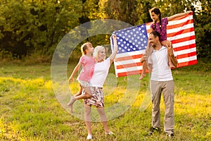 happy family with the flag of america USA at sunset outdoors