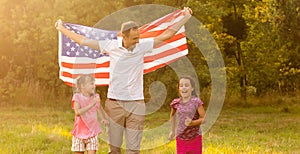 happy family with the flag of america USA at sunset outdoors