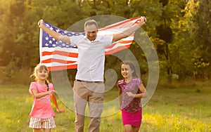 happy family with the flag of america USA at sunset outdoors