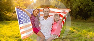 happy family with the flag of america USA at sunset outdoors