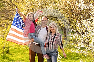 happy family with the flag of america USA at sunset outdoors