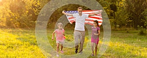 happy family with the flag of america USA at sunset outdoors