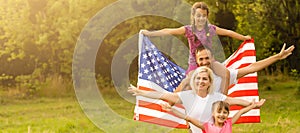 happy family with the flag of america USA at sunset outdoors